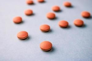 Small yellow orange beautiful medical pharmaceptic round pills, vitamins, drugs, antibiotics on a blue background, texture. Concept medicine, health care. Flat lay, top view photo