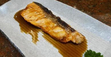 Grilled fresh salmon with Teriyaki sauce on white plate or dish at Japanese restaurant. Top view of Asian or fish food. Close up Barbeque seafood. photo