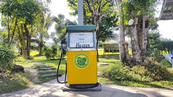 bangkok, tailandia - 25 de diciembre de 2020 gasolinera o gasolinera vintage amarilla y verde en sendero con camino y fondo de jardín. objeto de tecnología retro o antigua. foto