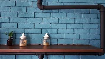 Glass bottle with dry flower inside and brown glass bottle and fake ornamental plant tree on wooden shelf with green brick wall for background and pipeline. Object decorative and loft style design. photo