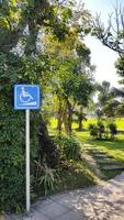 Blue signboard, sign or symbol for disabled wheelchairs to tell direction and way to get up cafe shop with pathway and garden park background. photo