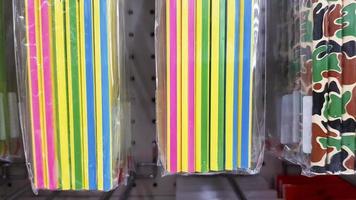 Close up colorful spine of book or notebook with plastic wrapping hanging on shelf at stationery store. Group of object or retail. photo