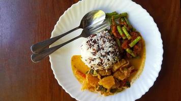 Top view of Three color rice with spicy yellow curry with pork and Stir fried pork belly and red curry paste with string bean in white dish on brown wooden background or table with copy space. photo