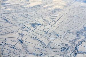 Aerial cloudscape view over clouds top to snow covered rivers, roads, cities and fields, winter air photo