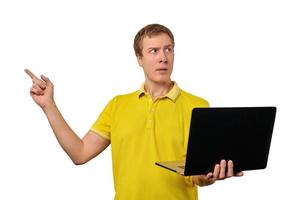 Puzzled young man with laptop pointing with finger isolated on white background, male confused face photo