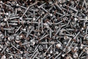 Bunch of galvanized self-drilling screws with washer and hexagonal head, hardware background photo