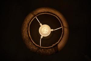 Incandescent lamp in round lampshade glowing in dark. photo