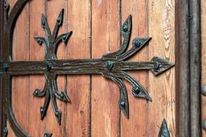 patrón forjado en la puerta con elementos decorativos. antigua entrada vintage, enorme puerta de madera pesada de iglesia o catedral. foto