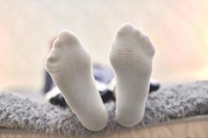 Woman resting on sofa in white striped socks, close up. photo