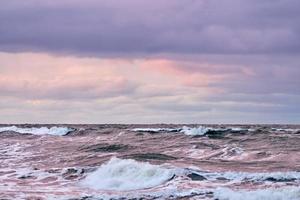 Purple cloudy sky and blue sea with foaming waves, seascape