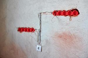 cajas de enchufe de plástico y cables eléctricos en la pared enyesada foto