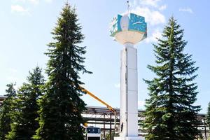 Repair of the tower clock. Workers on the crane repair clock-column, clock on the tower, paint, update, perform cosmetic repairs. Unusual clock against the blue sky photo