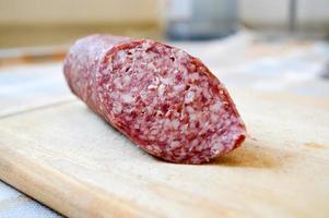 Delicious, appetizing red sausage salami on a birch cutting board photo