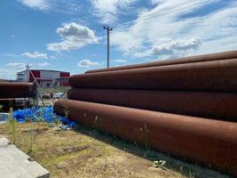 lotes de tuberías oxidadas de hierro industrial de gran diámetro con corrosión listas para la instalación de plomería para equipos de plantas petroquímicas de refinería de petróleo en el sitio de construcción foto