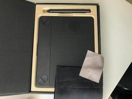 black graphic tablet with touch buttons. stylus for drawing on the surface. implementation of creative ideas. next to a microfiber cloth to wipe dust from the screen photo