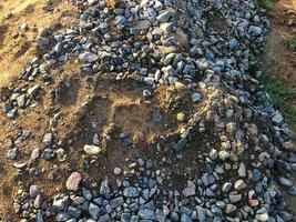 stones lie on the ground in black soil. many large stones are piled up. construction of new facilities. the builders put the stones and soil in one big heap photo