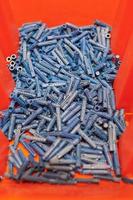 Plastic blue dowels on red background, wall plugs for fixation and installation, close up, top view photo