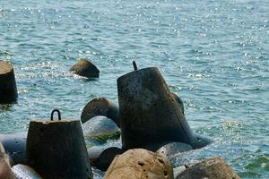 Large concrete breakwaters tetrapods near sea, close up. Blocks and stones, beautiful seascape photo