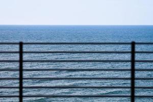 Fencing on observation deck, blue sea background, protection of tourists from falling off cliff photo