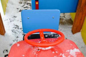 pequeño coche de juguete para niños con una rueda roja en un parque infantil en invierno foto