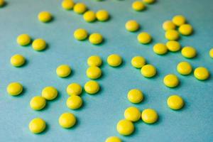 Small yellow orange beautiful medical pharmaceptic round pills, vitamins, drugs, antibiotics on a blue background, texture. Concept medicine, health care. Flat lay, top view photo