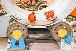 The process of manufacturing a cylindrical body for a container, a heat exchanger on rolls, by rolling, welding and orange helmets in the industrial premises of the workshop at an oil refinery photo