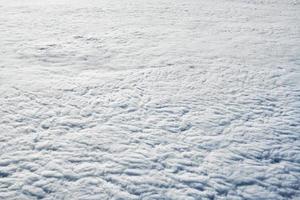 Over clouds top view from aircraft window, thick white blue clouds looks like soft foam photo