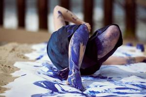 artista de performance femenina con vestido azul oscuro manchado con pintura de gouache azul con trazos anchos sobre lienzo foto