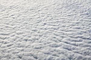 Breathtaking over clouds view from aircraft window, thick white blue clouds looks like soft foam photo