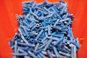 Plastic blue dowels on red background, wall plugs for fixation and installation, close up, top view photo