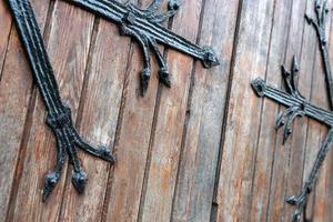 Forged pattern on door with decorative elements. Old vintage entrance, massive heavy wooden door of church or cathedral. photo