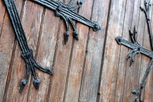 patrón forjado en la puerta con elementos decorativos. antigua entrada vintage, enorme puerta de madera pesada de iglesia o catedral. foto