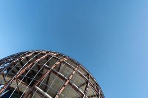 Unfinished sphere shape building, copy space. Construction of futuristic shopping mall or museum. Building constructed of concrete and reinforcement. photo