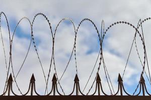 Barbed wire on fence, steel grating fence with barbs photo