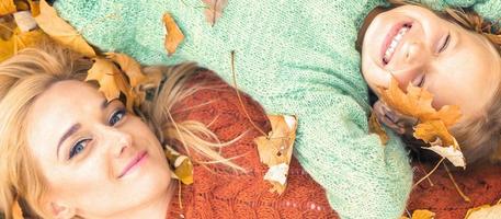 Girl and mom lying on autumn leaves photo