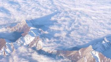 View from the airplane window to the snowy peaks of the mountains and white clouds. Inspiration Concept video