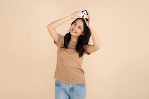 mujer joven feliz sosteniendo un modelo de casa de pie en el estudio foto