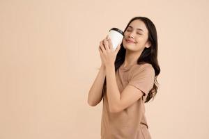 Happy young woman holding coffee cup standing in the studio photo