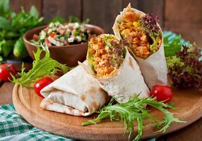 Burritos wraps with minced beef and vegetables on a wooden background photo