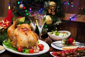 Baked turkey or chicken. The Christmas table is served with a turkey, decorated with bright tinsel and candles. Fried chicken, table. Christmas dinner. photo