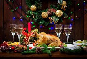 Baked turkey or chicken. The Christmas table is served with a turkey, decorated with bright tinsel and candles. Fried chicken, table. Christmas dinner. photo