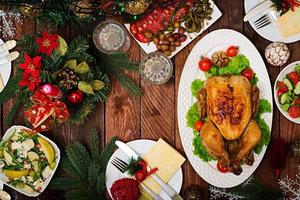 Baked turkey or chicken. The Christmas table is served with a turkey, decorated with bright tinsel and candles. Fried chicken, table. Christmas dinner. Flat lay. Top view photo