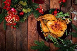 Baked turkey or chicken. The Christmas table is served with a turkey, decorated with bright tinsel and candles. Fried chicken, table. Christmas dinner. Flat lay. Top view photo