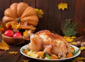 Roasted turkey garnished with cranberries on a rustic style table decorated with pumpkins, orange, apples and autumn leaf. Thanksgiving Day. photo