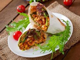 Burritos wraps with minced beef and vegetables on a wooden background photo