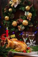 Baked turkey or chicken. The Christmas table is served with a turkey, decorated with bright tinsel and candles. Fried chicken, table. Christmas dinner. photo