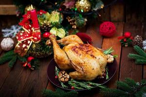 pavo o pollo al horno. la mesa navideña se sirve con un pavo, decorado con oropel brillante y velas. pollo frito, mesa. cena de Navidad.