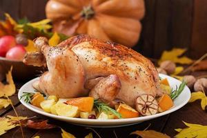 Roasted turkey garnished with cranberries on a rustic style table decorated with pumpkins, orange, apples and autumn leaf. Thanksgiving Day. photo