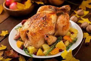 Roasted turkey garnished with cranberries on a rustic style table decorated with pumpkins, orange, apples and autumn leaf. Thanksgiving Day. photo