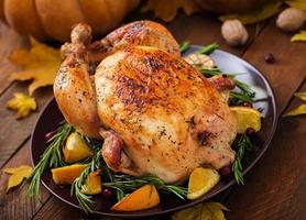 Roasted turkey garnished with cranberries on a rustic style table decorated with pumpkins, orange, apples and autumn leaf. Thanksgiving Day. photo